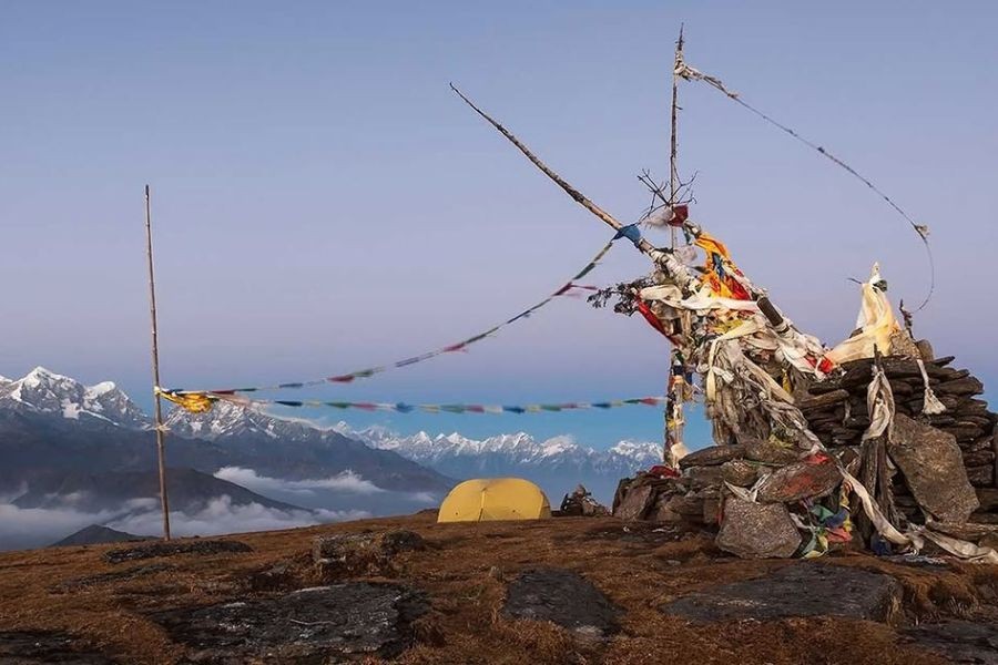 Prayer flags at Pikey Peak summit with Himalayan panorama.
